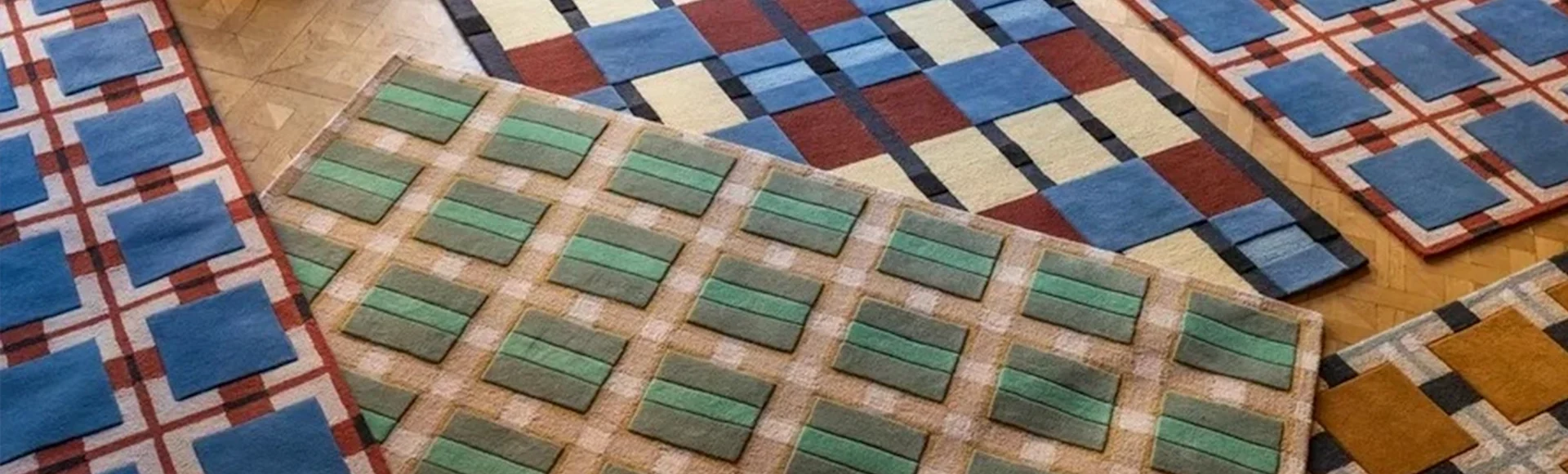 Närbild av flera färgglada mattor med olika geometriska mönster på ett trägolv.