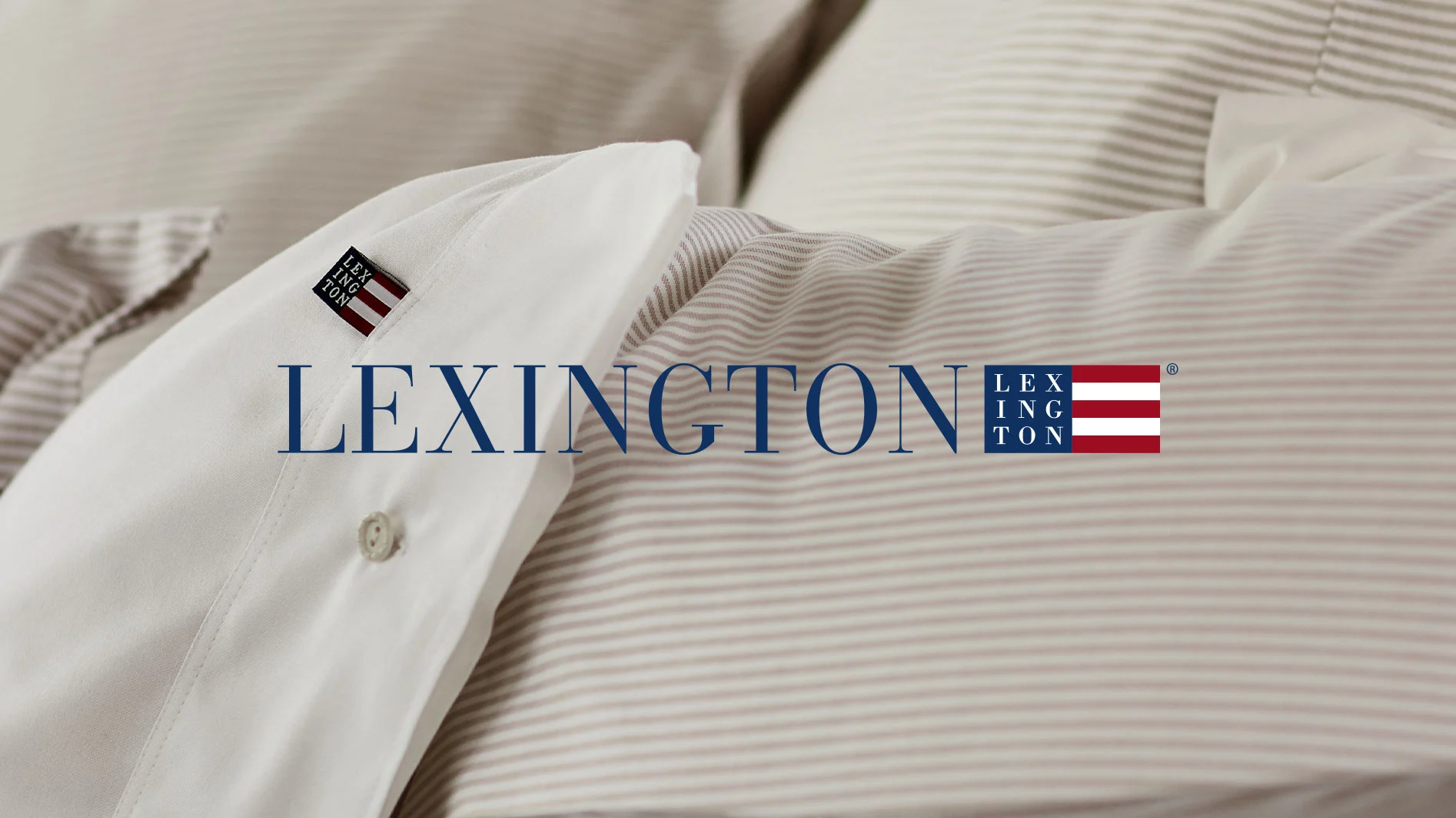 Lexington sängkläder med vit kudde och beige-randigt påslakan, med tydlig Lexington-logotyp.