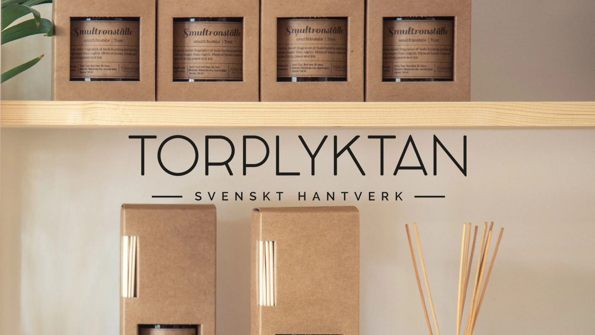 Stearinljus och doftpinnar på hyllor. Fyra askar med ljus på övre hyllan. Under, "TORPLYKTAN"-logotyp, "SVENSKT HANTVERK", och tre askar med doftpinnar.