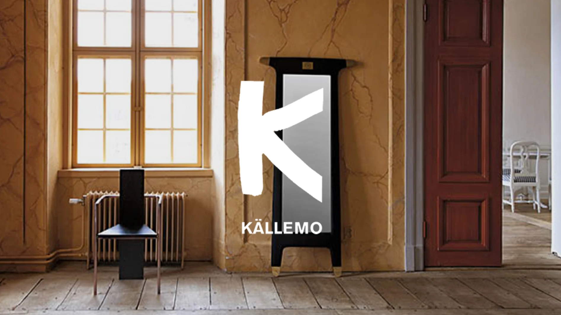 Källemo-logotyp i ett rum med en svart stol och en hög svart spegel med gulddetaljer.