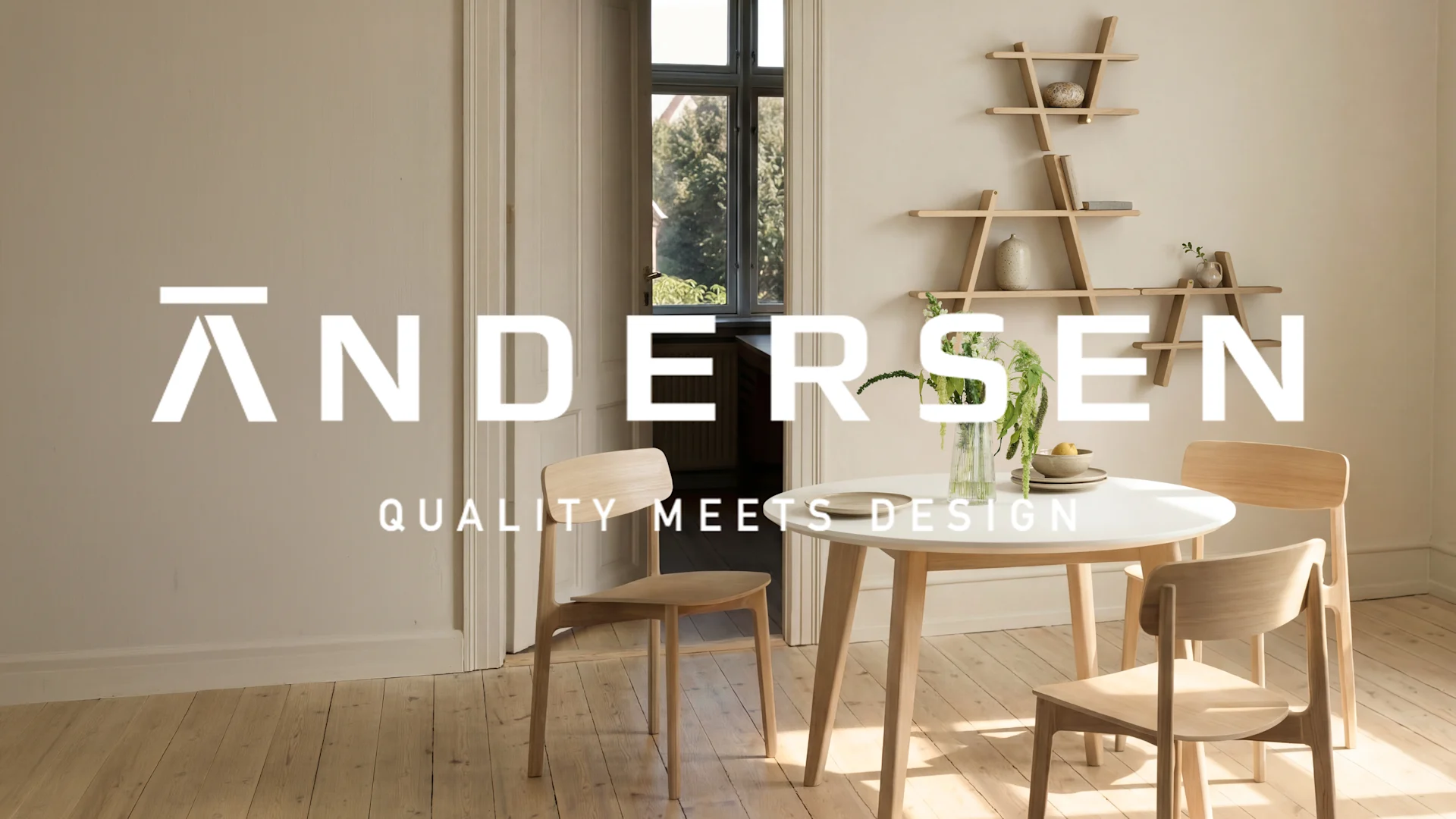 Modern matplats med runt vitt bord, fyra trästolar, växt och trähyllor på väggen. Text: ANDERSEN QUALITY MEETS DESIGN.